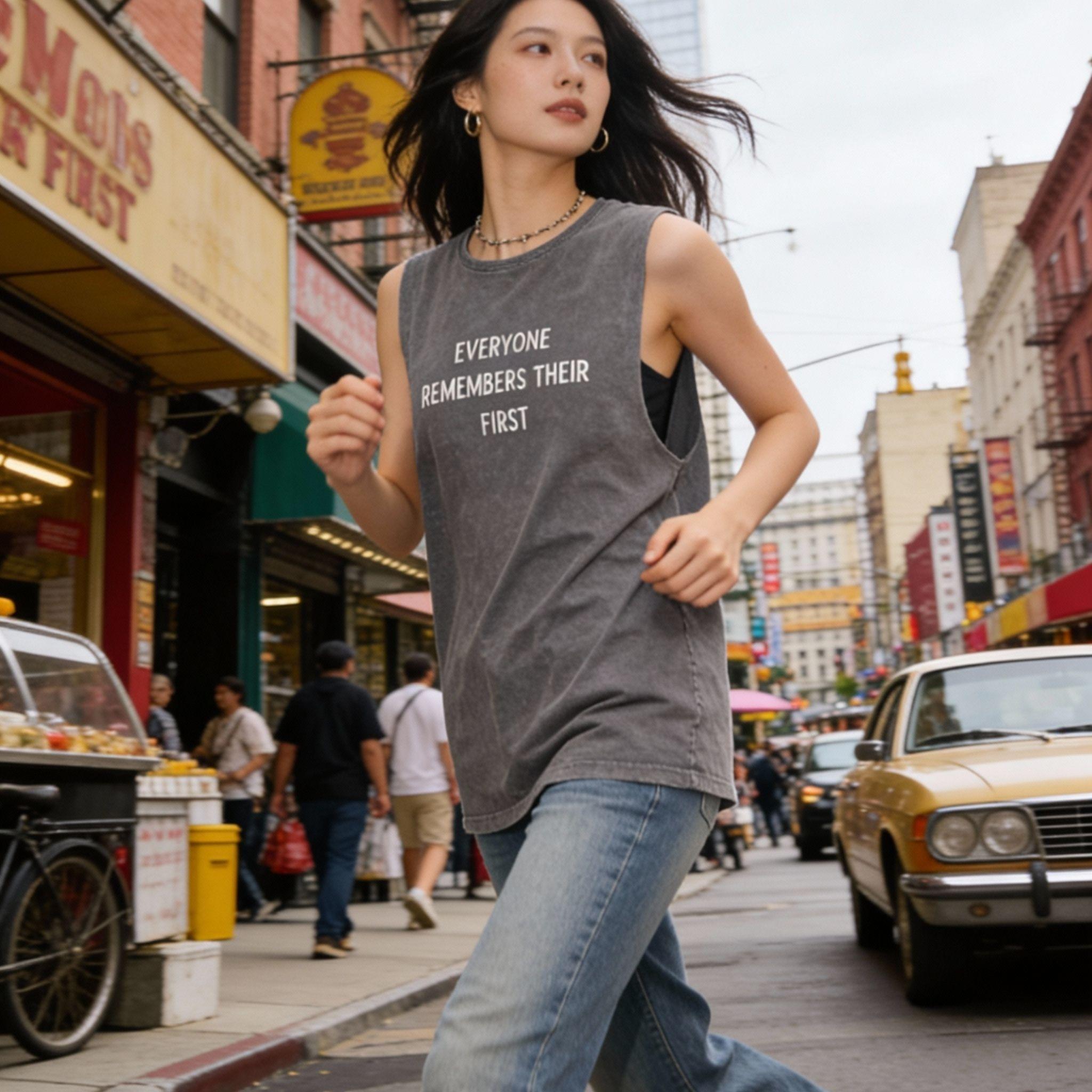 Model posing in front of modern city architecture with a mineral wash tank top.