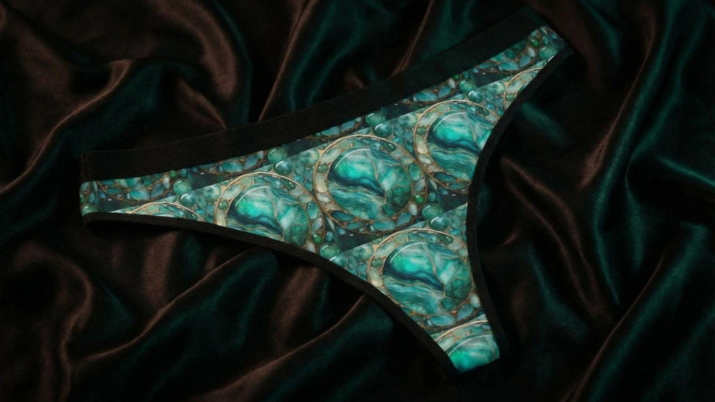 A stylish boudoir shoot in a dark bedroom with an emerald-patterned thong.